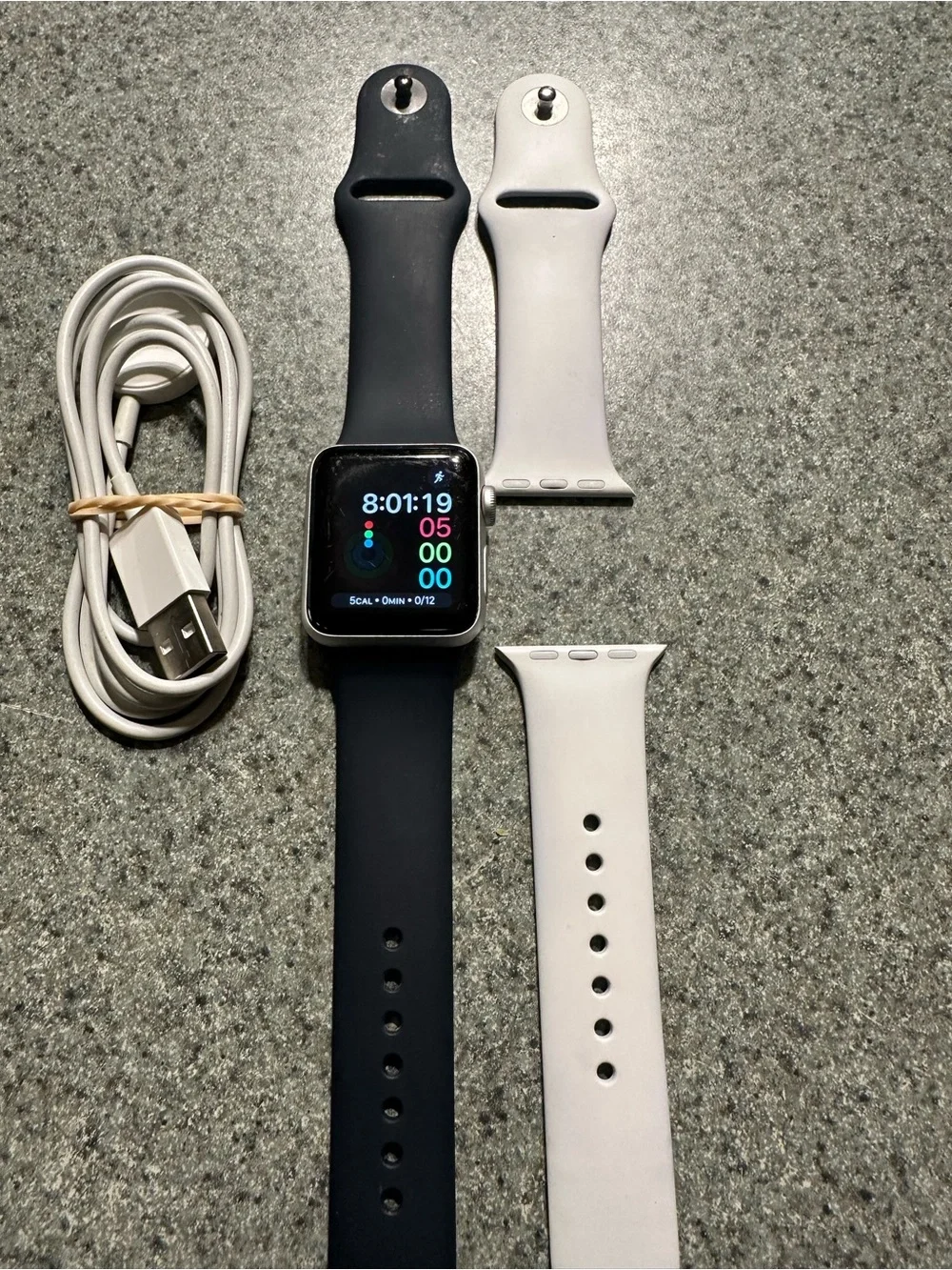 Apple Watch Series 3 with Black and White bands and charging cable.